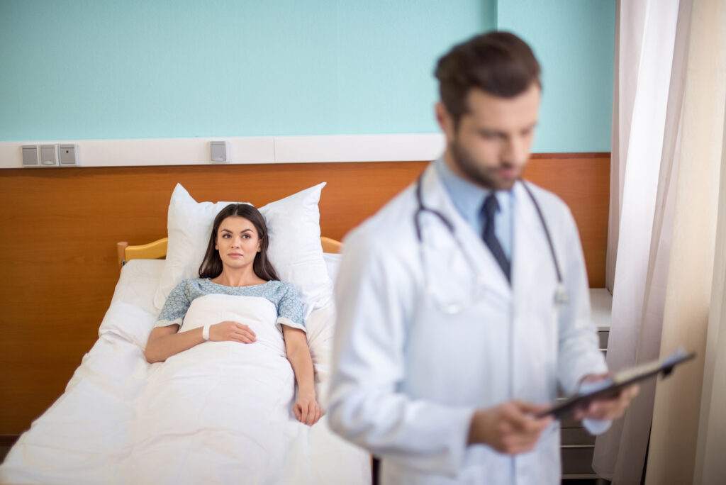 Doctor standing in front of patient in bed.